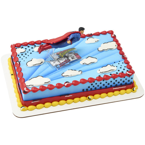 Superman-themed birthday cake with toy figure on a white background